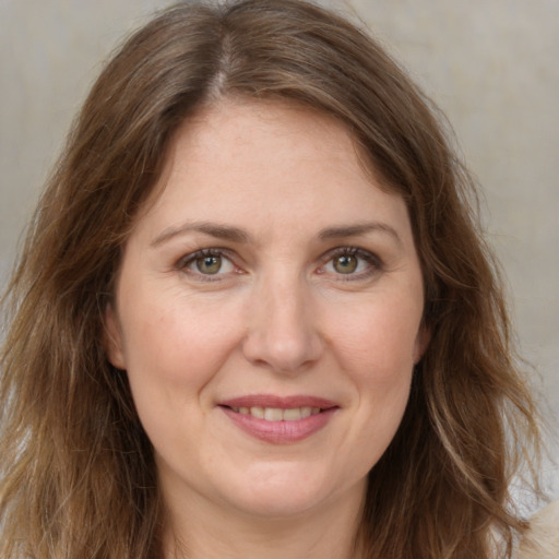 Joyful white adult female with long  brown hair and green eyes