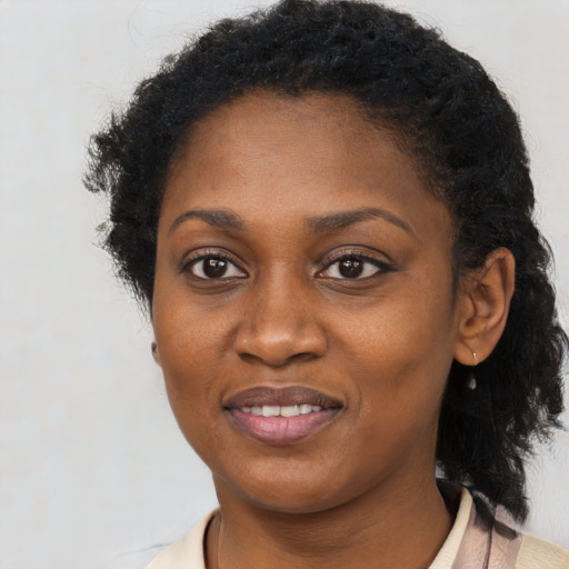 Joyful black young-adult female with long  brown hair and brown eyes