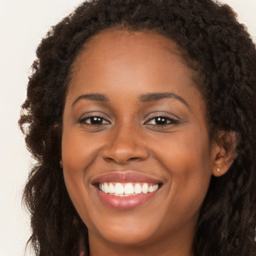 Joyful black young-adult female with long  brown hair and brown eyes