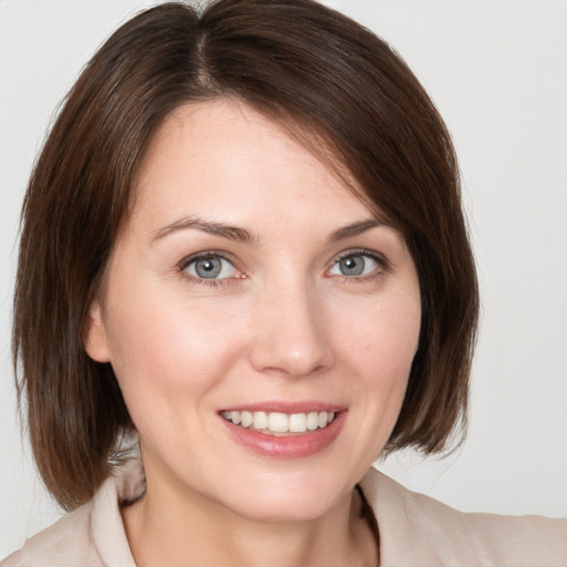 Joyful white young-adult female with medium  brown hair and grey eyes