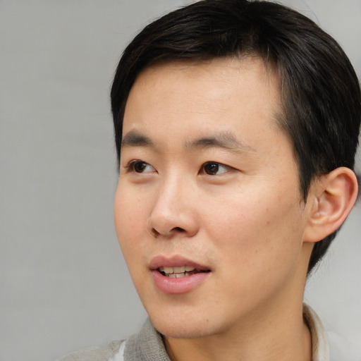 Joyful asian young-adult male with short  black hair and brown eyes