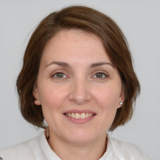 Joyful white young-adult female with medium  brown hair and grey eyes