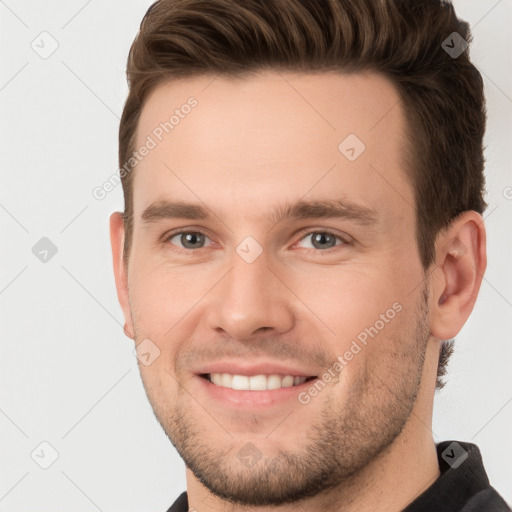 Joyful white young-adult male with short  brown hair and grey eyes