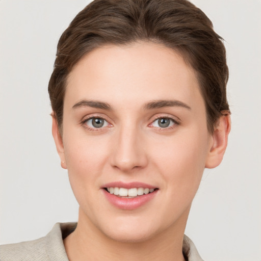 Joyful white young-adult female with short  brown hair and grey eyes