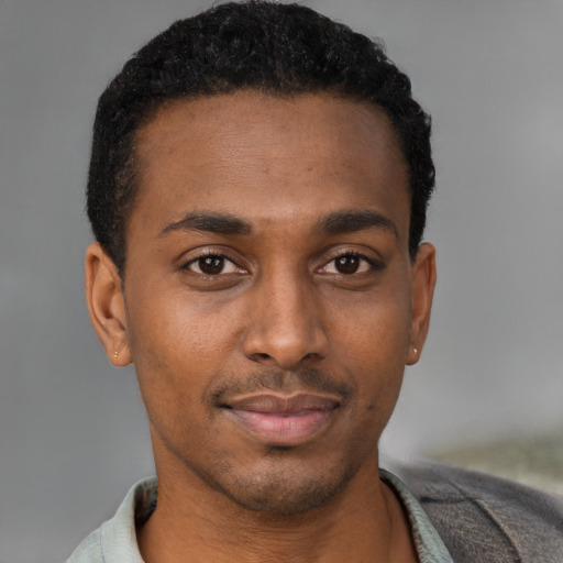 Joyful black young-adult male with short  brown hair and brown eyes