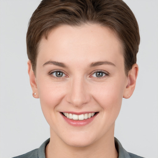 Joyful white young-adult female with short  brown hair and grey eyes