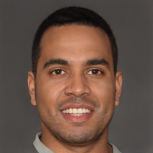 Joyful black young-adult male with short  brown hair and brown eyes
