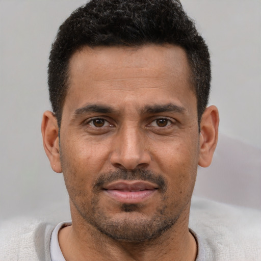 Joyful black young-adult male with short  brown hair and brown eyes