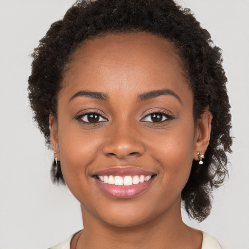 Joyful black young-adult female with long  brown hair and brown eyes