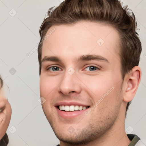 Joyful white young-adult male with short  brown hair and grey eyes