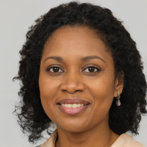 Joyful black young-adult female with long  brown hair and brown eyes