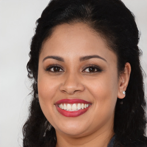 Joyful black young-adult female with long  brown hair and brown eyes