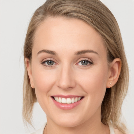 Joyful white young-adult female with medium  brown hair and grey eyes