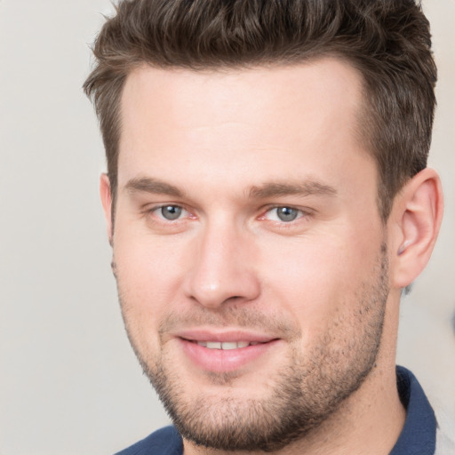 Joyful white young-adult male with short  brown hair and grey eyes