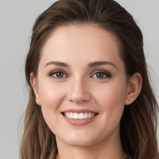 Joyful white young-adult female with long  brown hair and grey eyes