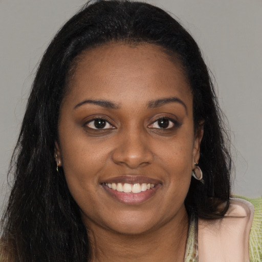 Joyful black young-adult female with long  brown hair and brown eyes