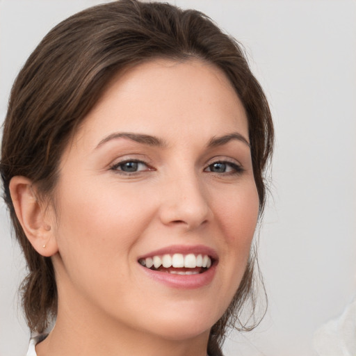 Joyful white young-adult female with medium  brown hair and grey eyes