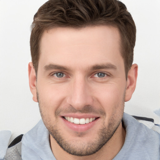 Joyful white young-adult male with short  brown hair and grey eyes