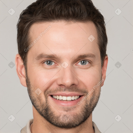 Joyful white young-adult male with short  brown hair and grey eyes