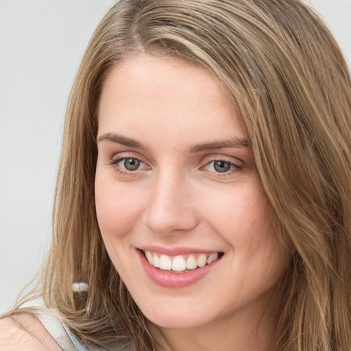 Joyful white young-adult female with long  brown hair and blue eyes