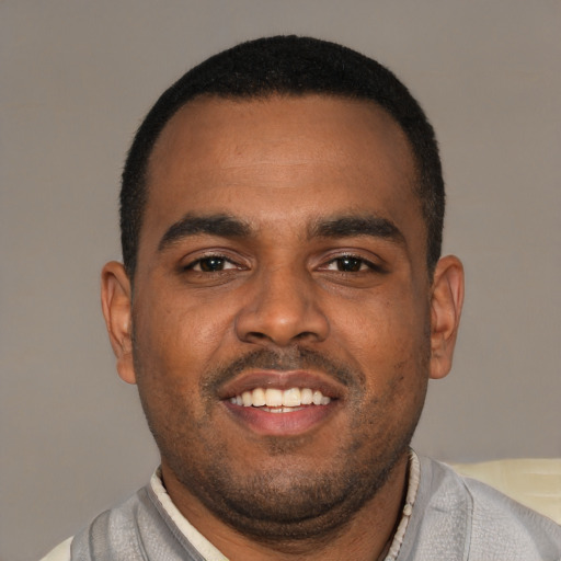 Joyful black young-adult male with short  brown hair and brown eyes