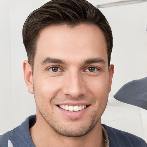 Joyful white young-adult male with short  brown hair and grey eyes