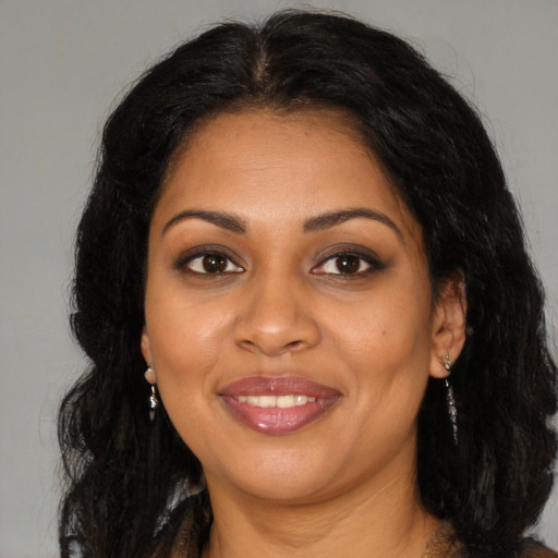 Joyful black young-adult female with long  brown hair and brown eyes
