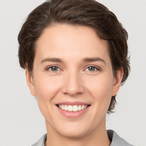 Joyful white young-adult female with short  brown hair and grey eyes