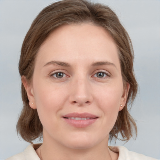 Joyful white young-adult female with medium  brown hair and grey eyes