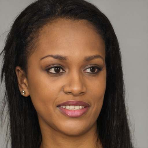 Joyful black young-adult female with long  brown hair and brown eyes