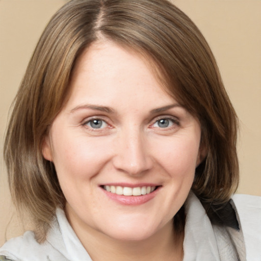 Joyful white adult female with medium  brown hair and blue eyes