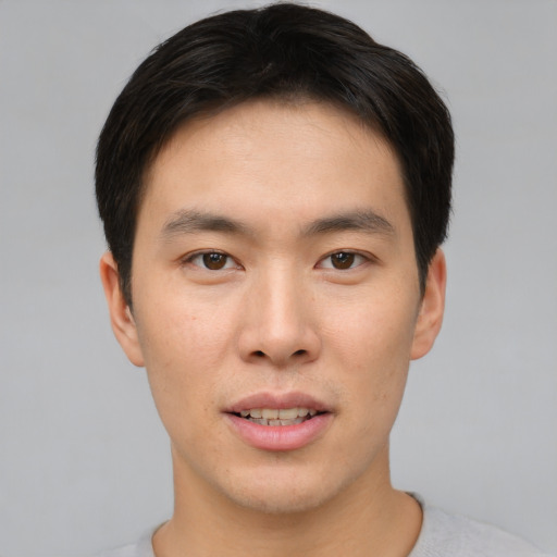 Joyful asian young-adult male with short  brown hair and brown eyes