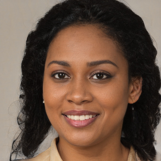 Joyful black young-adult female with long  brown hair and brown eyes