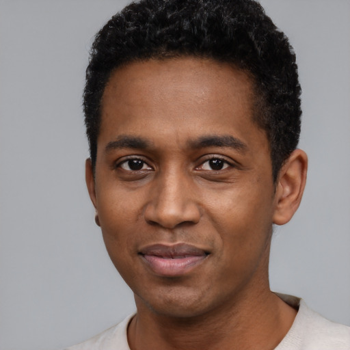 Joyful black young-adult male with short  black hair and brown eyes