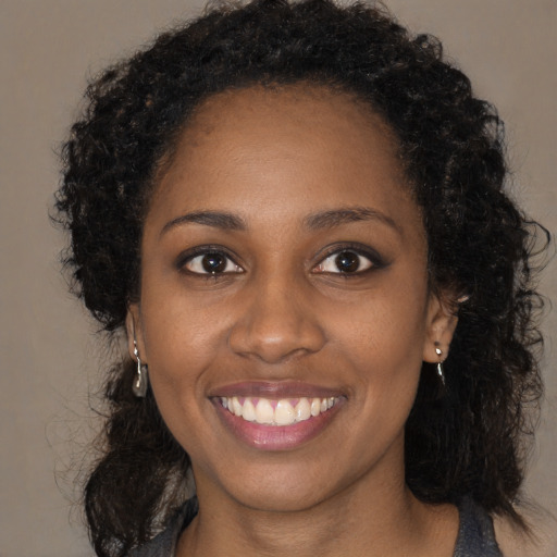Joyful black young-adult female with long  brown hair and brown eyes