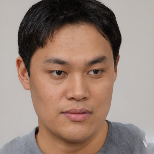 Joyful asian young-adult male with short  brown hair and brown eyes
