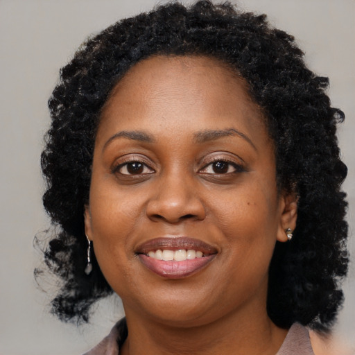Joyful black young-adult female with long  black hair and brown eyes