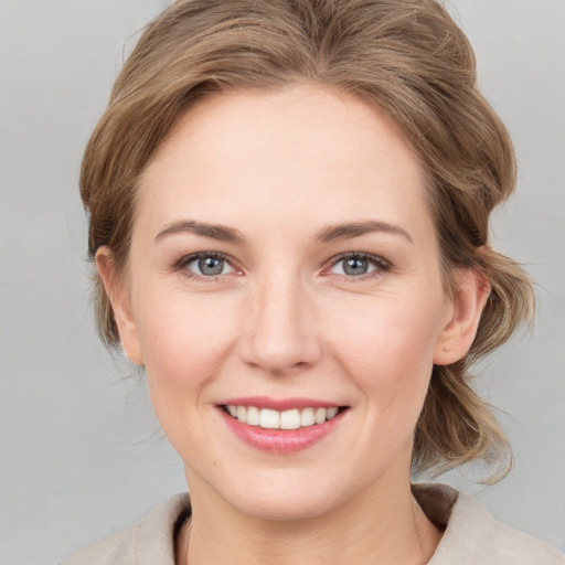 Joyful white young-adult female with medium  brown hair and grey eyes