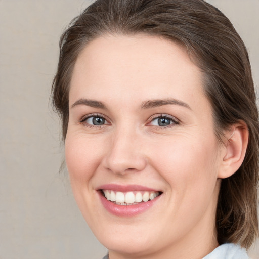 Joyful white young-adult female with medium  brown hair and grey eyes