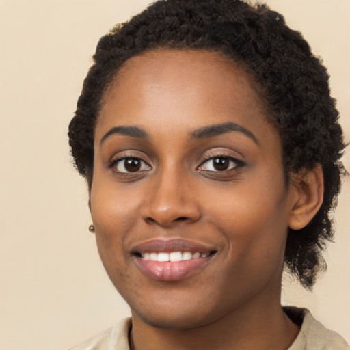 Joyful black young-adult female with long  black hair and brown eyes