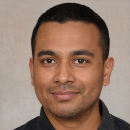 Joyful latino young-adult male with short  black hair and brown eyes