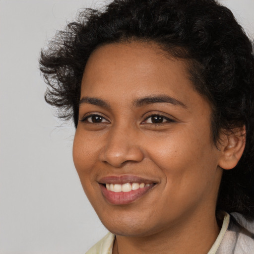 Joyful black young-adult female with long  brown hair and brown eyes