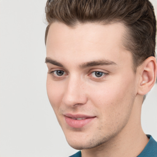 Joyful white young-adult male with short  brown hair and grey eyes