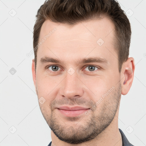 Joyful white young-adult male with short  brown hair and grey eyes