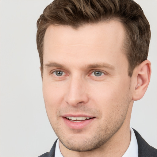 Joyful white young-adult male with short  brown hair and grey eyes