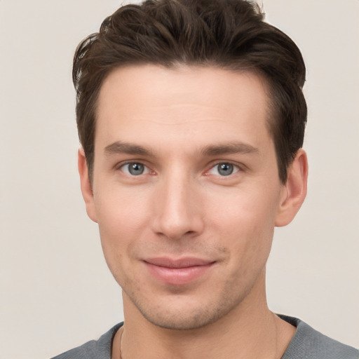 Joyful white young-adult male with short  brown hair and grey eyes