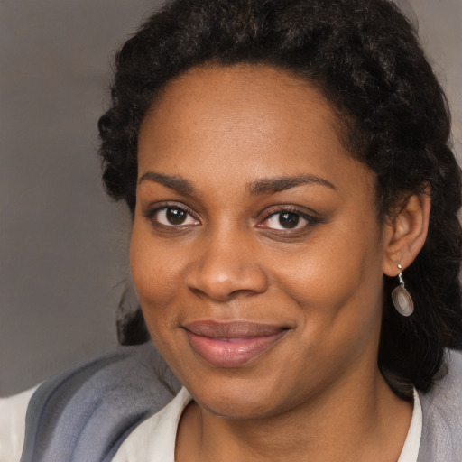 Joyful black young-adult female with long  brown hair and brown eyes