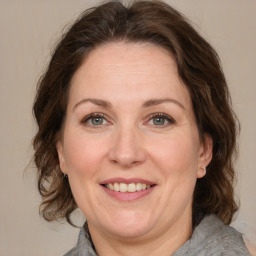 Joyful white adult female with medium  brown hair and green eyes