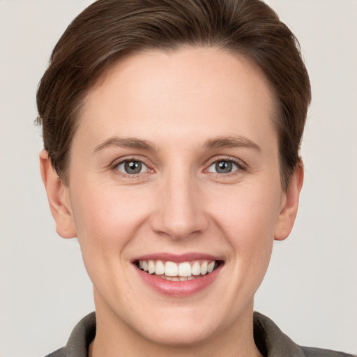 Joyful white young-adult female with short  brown hair and grey eyes