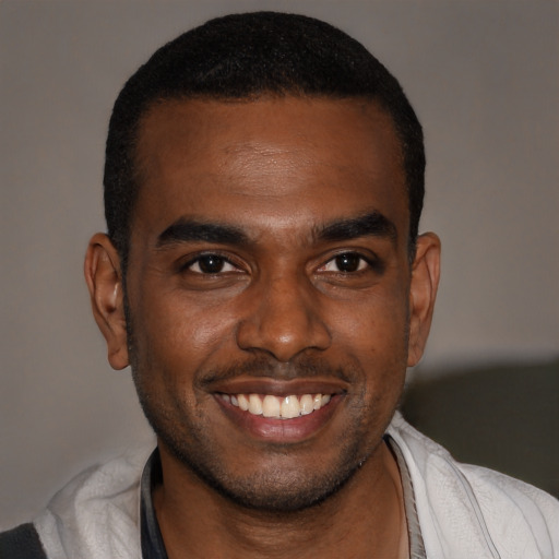 Joyful black young-adult male with short  brown hair and brown eyes